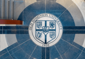 Overhead view of a circular Old Dominion University emblem on the floor, surrounded by geometric tile patterns.